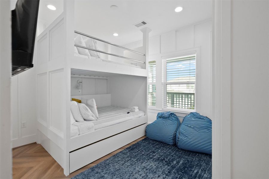 Blending smart design with coastal elegance, this second-floor family bedroom features a custom-built bunk bed with a hidden trundle—ideal for accommodating guests or little ones in style. The crisp white palette, ocean-inspired hues, and soft natural light evoke a serene beachside escape, while casual comforts like plush beanbags add a touch of laid-back luxury perfect for modern family living. Blending smart design with coastal elegance, this second-floor family bedroom features a custom-built bunk bed with a hidden trundle—ideal for accommodating guests or little ones in style. The crisp white palette, ocean-inspired hues, and soft natural light evoke a serene beachside escape, while casual comforts like plush beanbags add a touch of laid-back luxury perfect for modern family living.