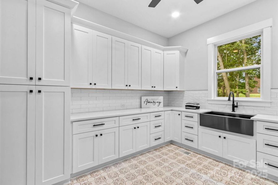 Other side of laundry with more cabinets than many kitchens. Has black stainless sink & quartz counters.