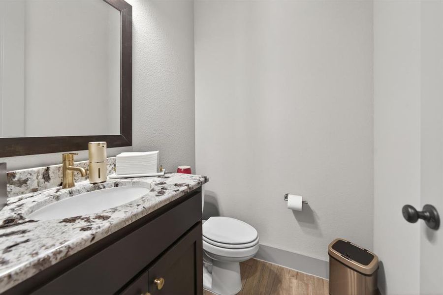 Half bathroom featuring vanity, light wood-style flooring, and a textured wall Half bathroom featuring vanity, light wood-style flooring, and a textured wall