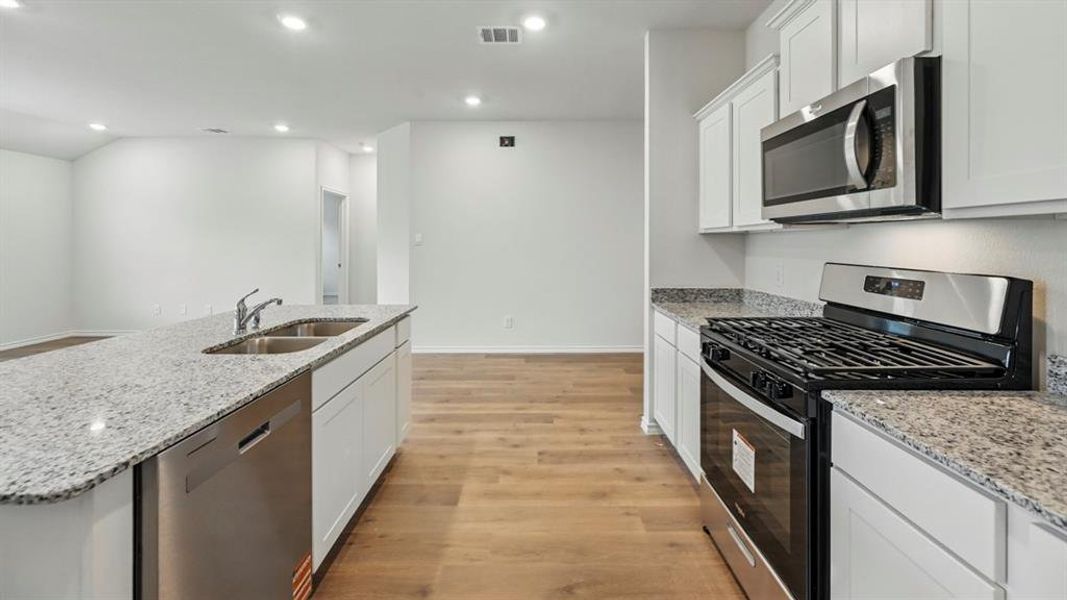 Kitchen featuring an expansive island with a double basin sink, stainless steel dishwasher, and stone countertops