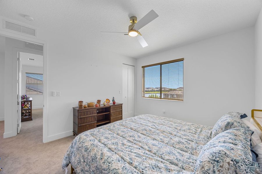 Bedroom with a textured ceiling, light carpet, ceiling fan, and a closet