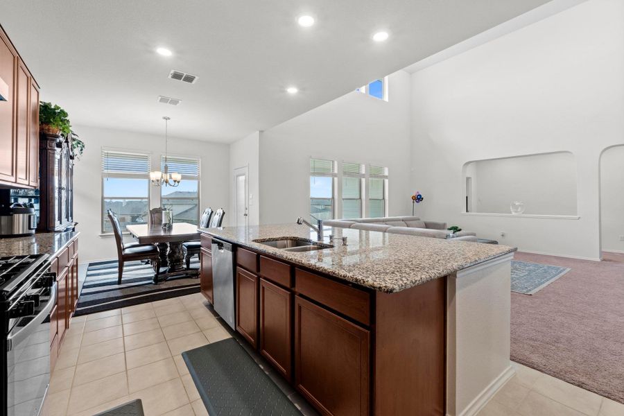 Kitchen island with granite countertops and integrated stainless steel sink, complemented by wood-finish cabinetry