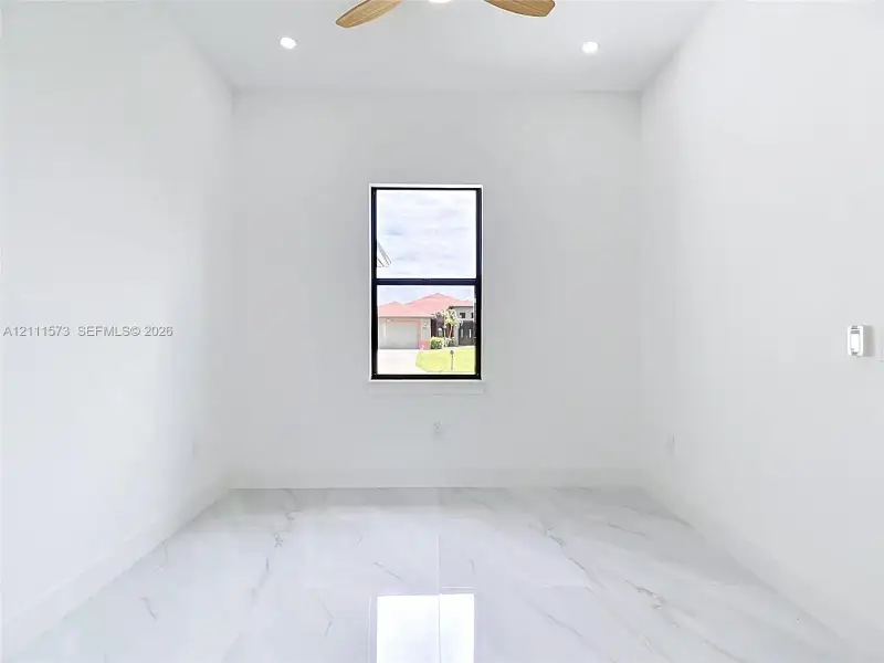 Large-format polished tile flooring, central ceiling fan, recessed lighting, and single-pane window with black framing