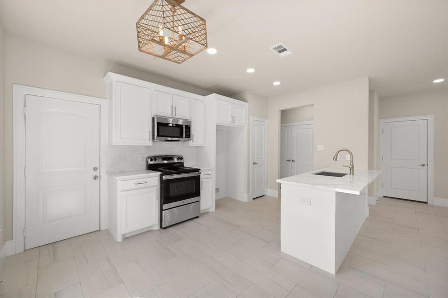 Kitchen featuring decorative backsplash, sink, stainless steel appliances, and light tile patterned floors