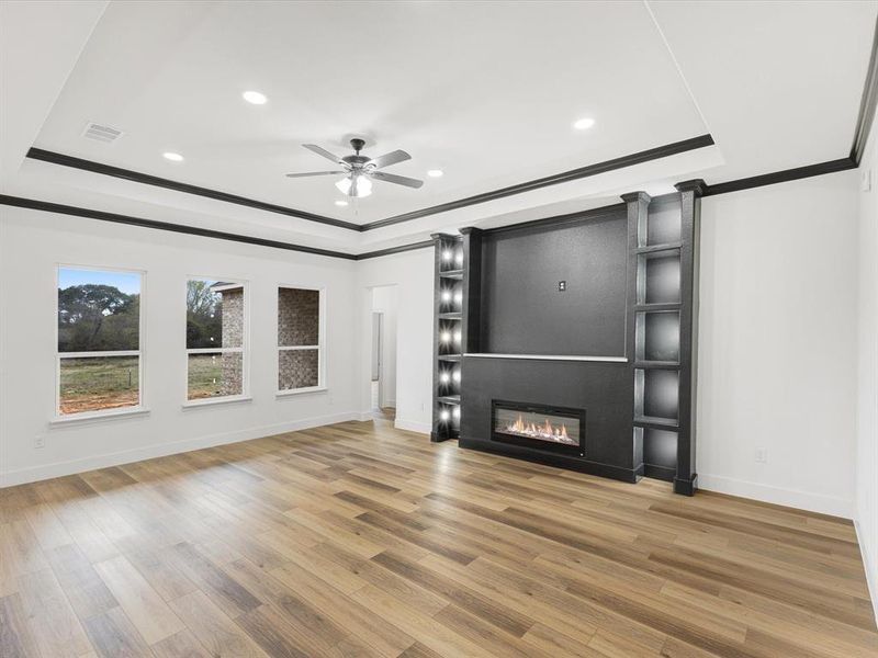 Unfurnished living room featuring crown molding, recessed lighting, light wood-type flooring, a fireplace, and a ceiling fan Unfurnished living room featuring crown molding, recessed lighting, light wood-type flooring, a fireplace, and a ceiling fan