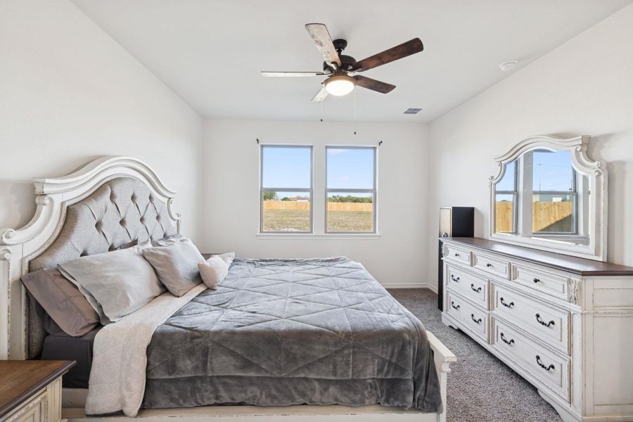 Carpeted bedroom featuring a ceiling fan and baseboards Carpeted bedroom featuring a ceiling fan and baseboards