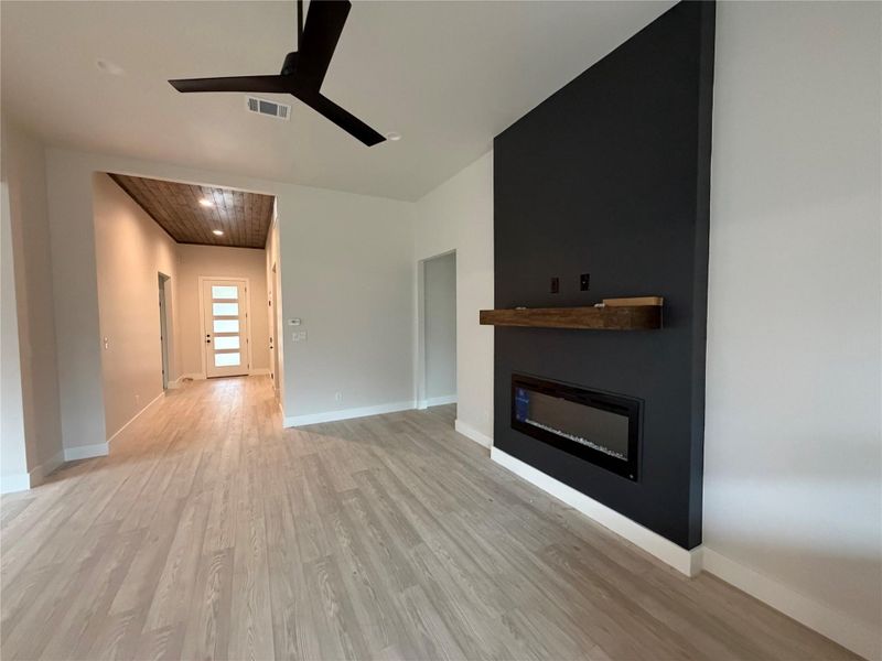 A striking black accent wall showcases a modern fireplace, complemented by durable wood flooring throughout.