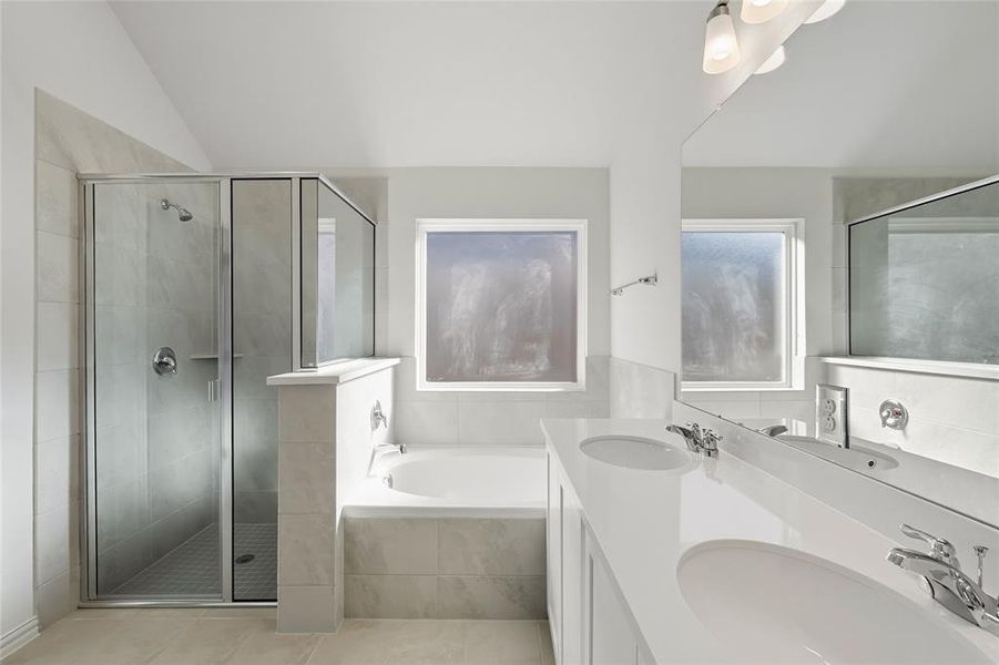 Full bath with a bath, a stall shower, double vanity, light tile patterned floors, and vaulted ceiling Full bath with a bath, a stall shower, double vanity, light tile patterned floors, and vaulted ceiling