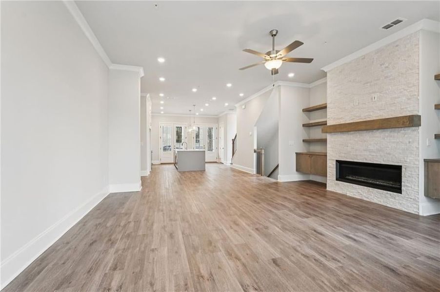 Unfurnished living room with a fireplace, light wood-type flooring, a ceiling fan, crown molding, and recessed lighting