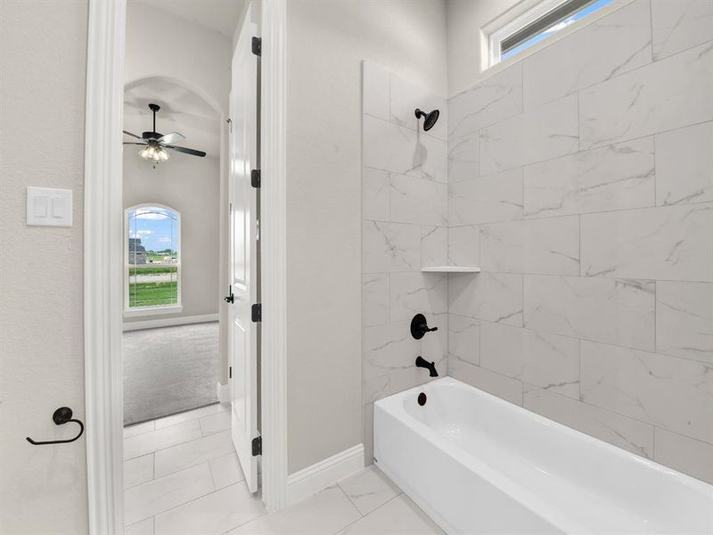 Bathroom featuring healthy amount of natural light, ceiling fan, washtub / shower combination, and baseboards Bathroom featuring healthy amount of natural light, ceiling fan, washtub / shower combination, and baseboards