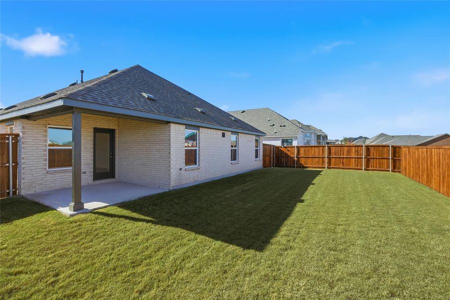 Rear view of property with brick siding, a patio, a fenced backyard, and a shingled roof