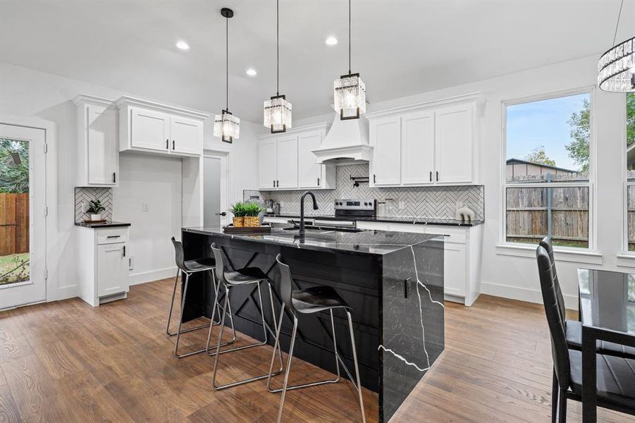 Kitchen featuring white cabinetry, plenty of natural light, an island with sink, and hardwood / wood-style floors