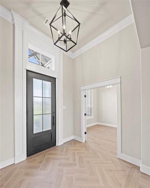 Foyer entrance featuring a chandelier and crown molding