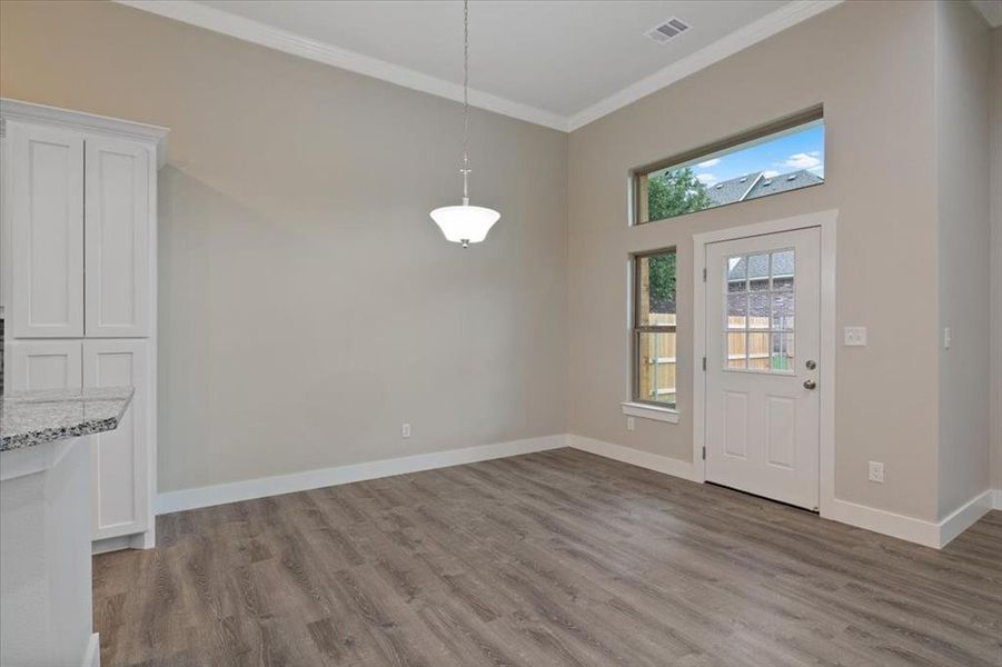 Entryway with ornamental molding, hardwood / wood-style floors, and a towering ceiling