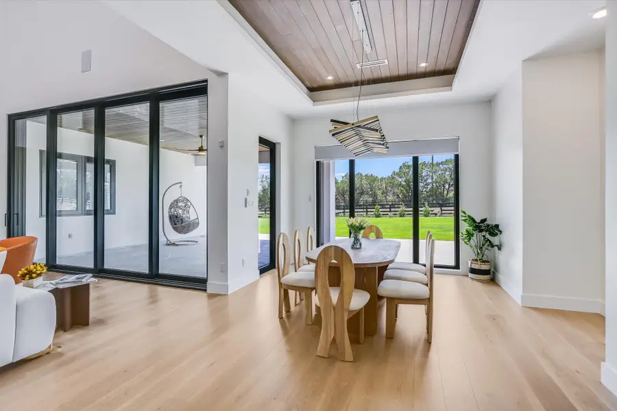 Dining room featuring a tray ceiling, wood ceiling, light wood floors, and recessed lighting as well as custom chandelier Dining room featuring a tray ceiling, wood ceiling, light wood floors, and recessed lighting as well as custom chandelier