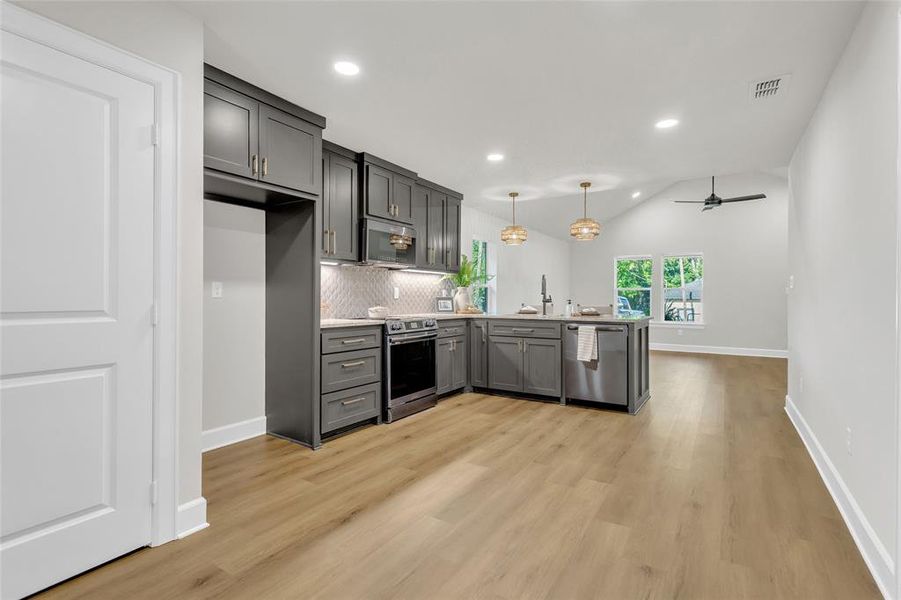 Kitchen featuring a peninsula, lofted ceiling, recessed lighting, gray cabinetry, and a ceiling fan Kitchen featuring a peninsula, lofted ceiling, recessed lighting, gray cabinetry, and a ceiling fan