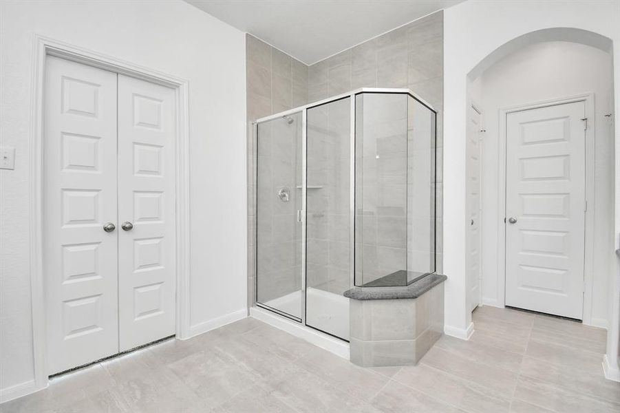 The walk-in shower features tile surround and a sitting area.