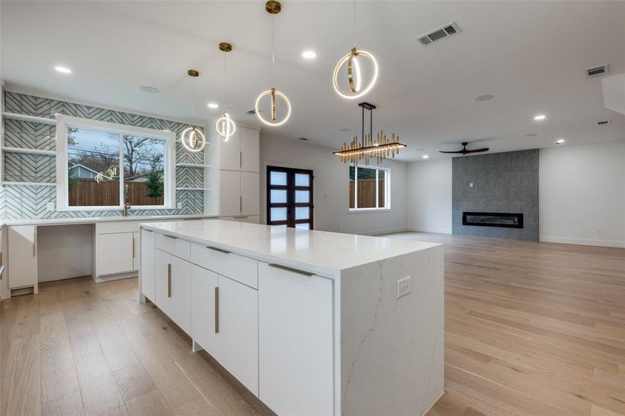 Kitchen with white cabinets, modern cabinets, decorative light fixtures, light wood-type flooring, and recessed lighting