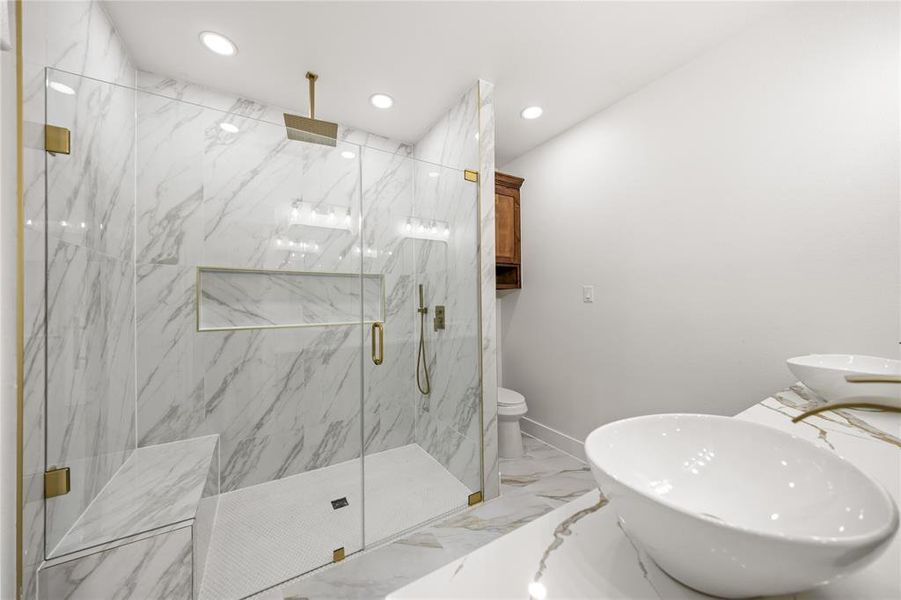 Bathroom featuring light marble finish flooring, a marble finish shower, recessed lighting, and double vanity