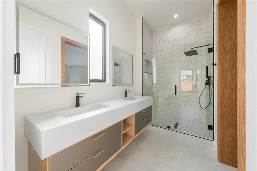 Bathroom featuring double vanity, a stall shower, and light tile patterned floors Bathroom featuring double vanity, a stall shower, and light tile patterned floors