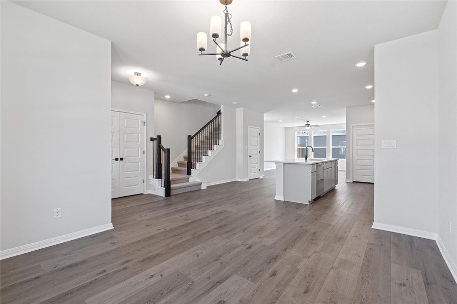 Unfurnished living room featuring a chandelier, stairway, wood finished floors, recessed lighting, and ceiling fan