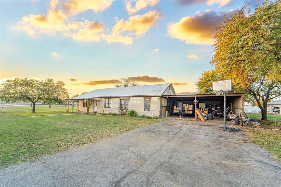 View of front of property with a front lawn, driveway, a metal roof, and a carport View of front of property with a front lawn, driveway, a metal roof, and a carport