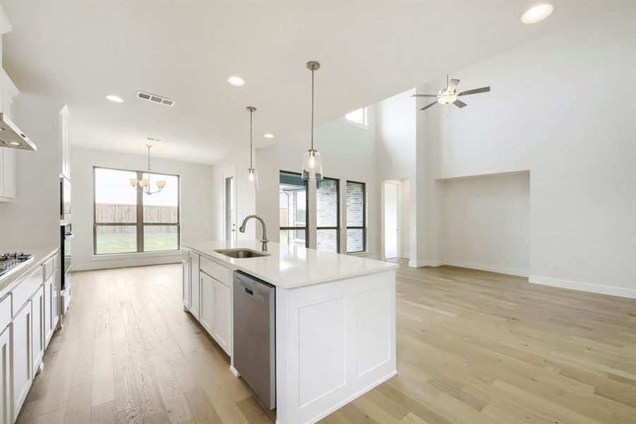 Contemporary kitchen island with a built-in sink, stainless steel dishwasher, and pendant lighting Contemporary kitchen island with a built-in sink, stainless steel dishwasher, and pendant lighting