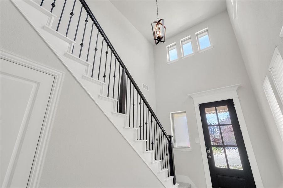 Entry foyer featuring a grand staircase with wrought iron balusters and white risers