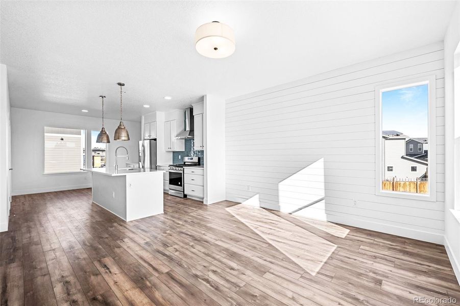 Main level open concept living area includes a large living room, kitchen with large island, dining area with additional cabinets, & half bath.