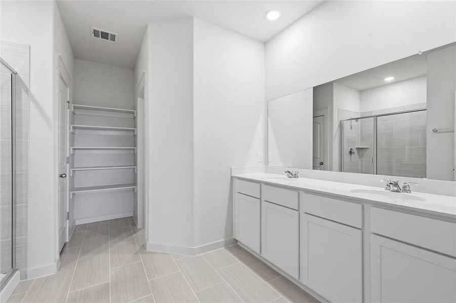 Dual vanity with white cabinetry and integrated sinks, large wall-mounted mirror, and tile flooring Dual vanity with white cabinetry and integrated sinks, large wall-mounted mirror, and tile flooring