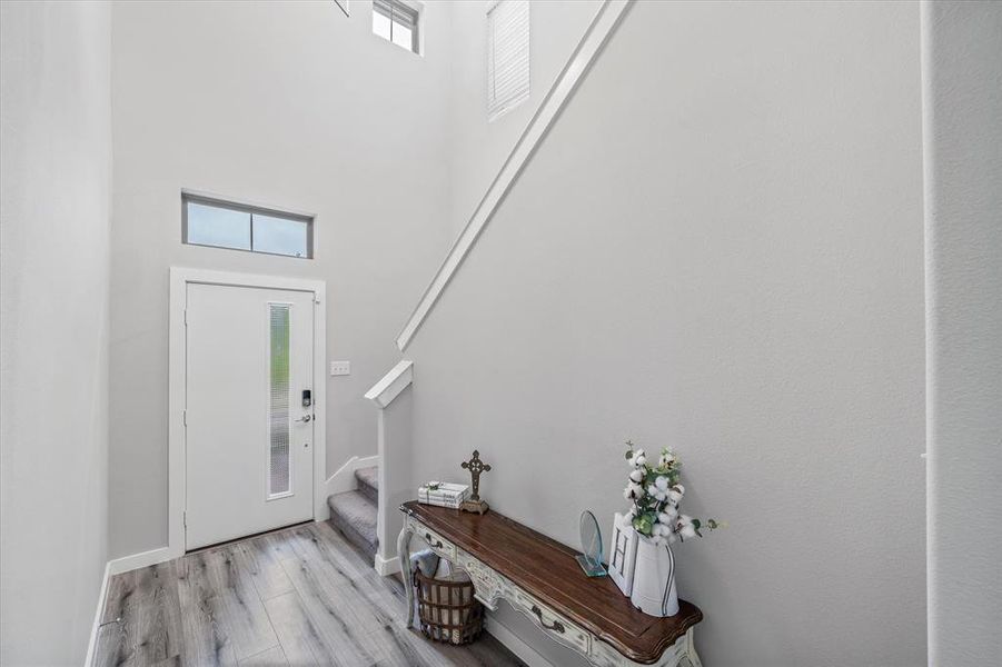 Entryway featuring a towering ceiling, a wealth of natural light, and light hardwood / wood-style flooring