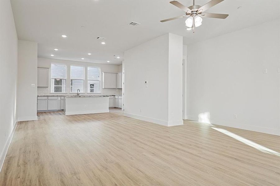 Unfurnished living room featuring visible vents, baseboards, light wood-style flooring, and a ceiling fan