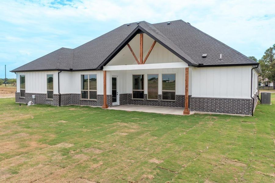 Rear view of house with roof with shingles, a yard, a patio, and brick siding