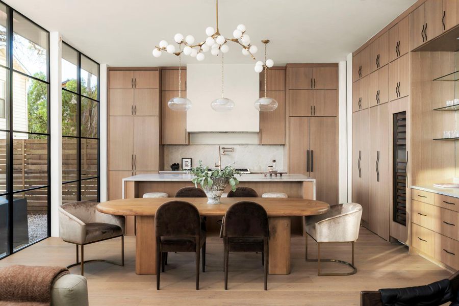 Kitchen with a kitchen island, light wood-style floors, wine cooler, light wood finish cabinetry, and decorative light fixtures