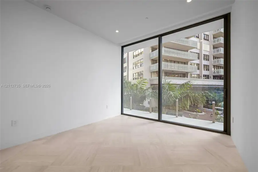 Floor-to-ceiling sliding glass door, recessed lighting, and light-toned wood-finish flooring arranged in a parquet pattern
