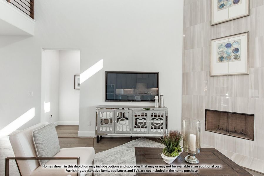 Living room with two-story ceiling, tile fireplace, wall-mounted TV, and hardwood floors Living room with two-story ceiling, tile fireplace, wall-mounted TV, and hardwood floors