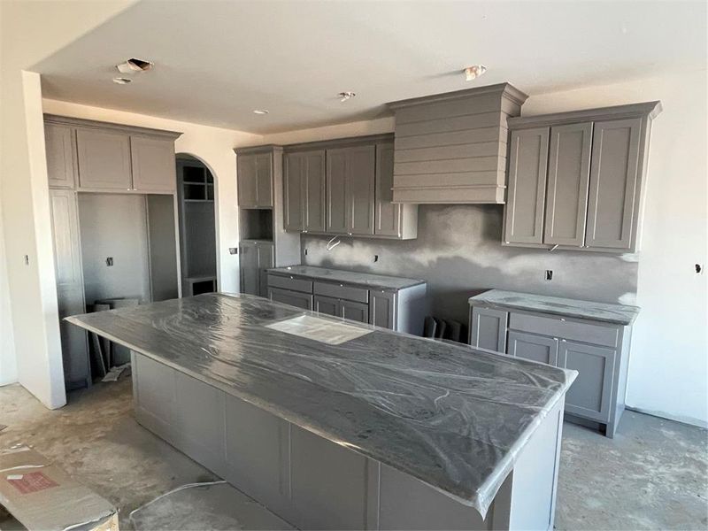 Kitchen with dark stone countertops, gray cabinets, and a kitchen island