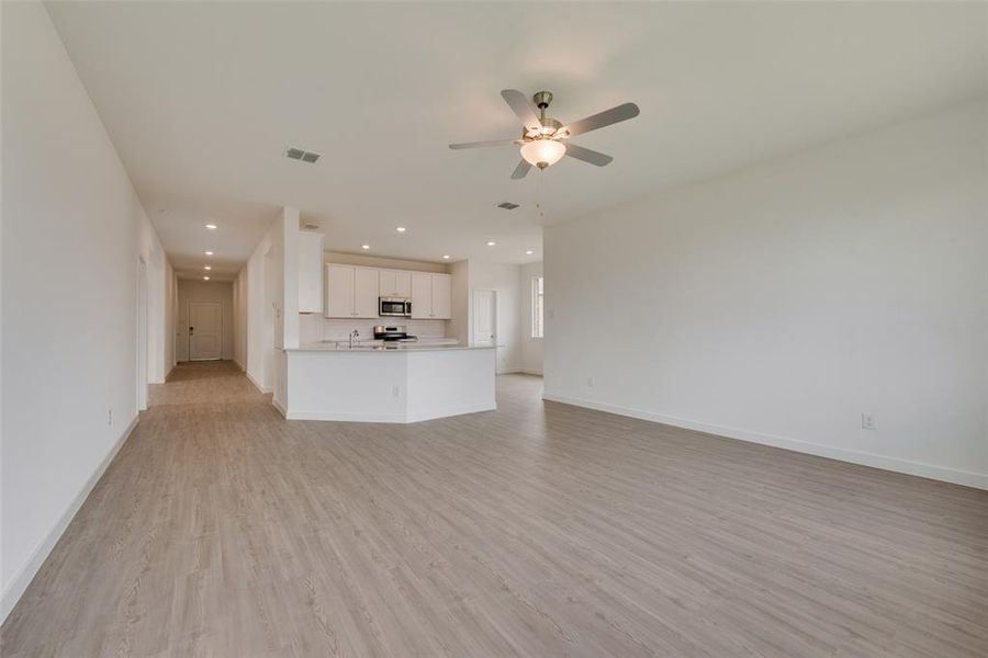 Unfurnished living room with sink, light wood-type flooring, and ceiling fan