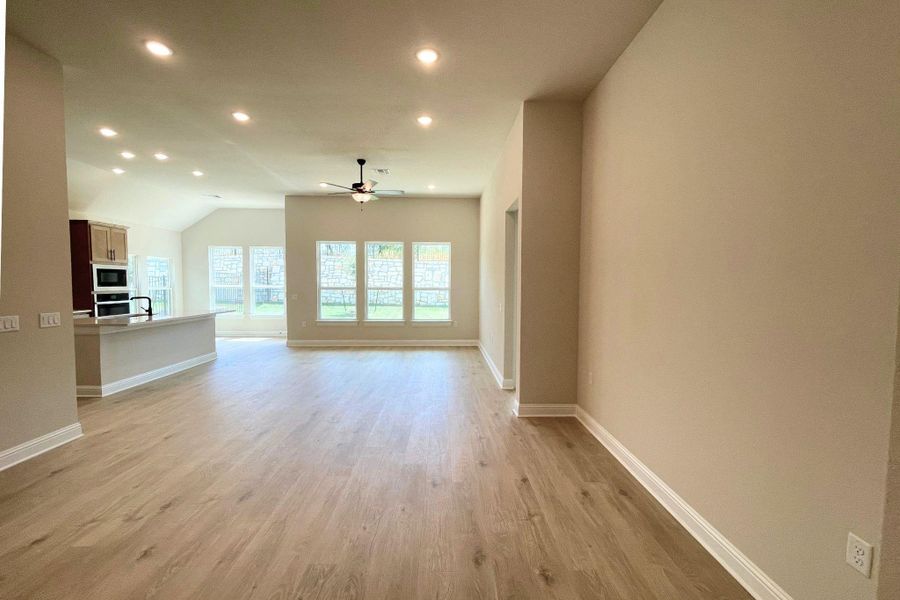 Recessed lighting illuminates wood-look flooring and clean architectural lines across a fluid living design. Recessed lighting illuminates wood-look flooring and clean architectural lines across a fluid living design.
