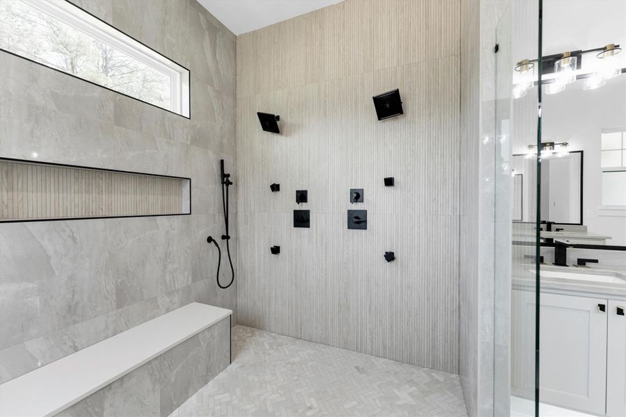 Luxuriate in this elegant bathroom featuring a sleek freestanding tub, modern fixtures, and stylish gray tile. Perfect for relaxation and unwinding.