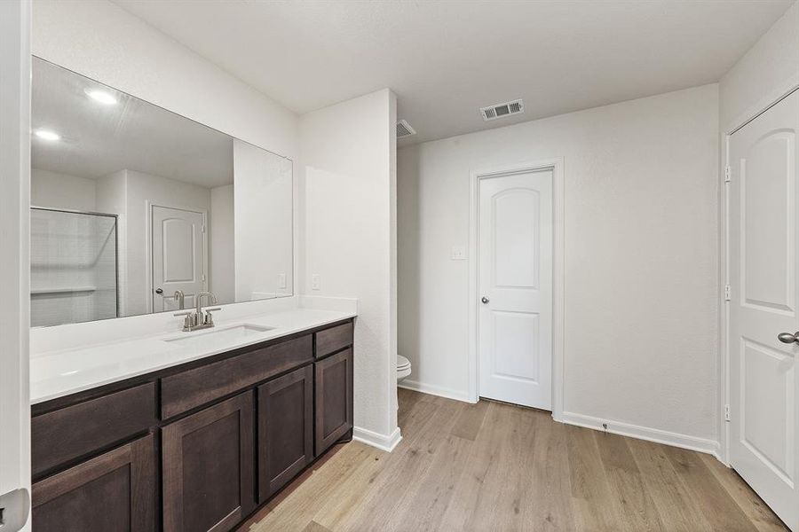 Full bathroom featuring visible vents, baseboards, toilet, wood finished floors, and vanity