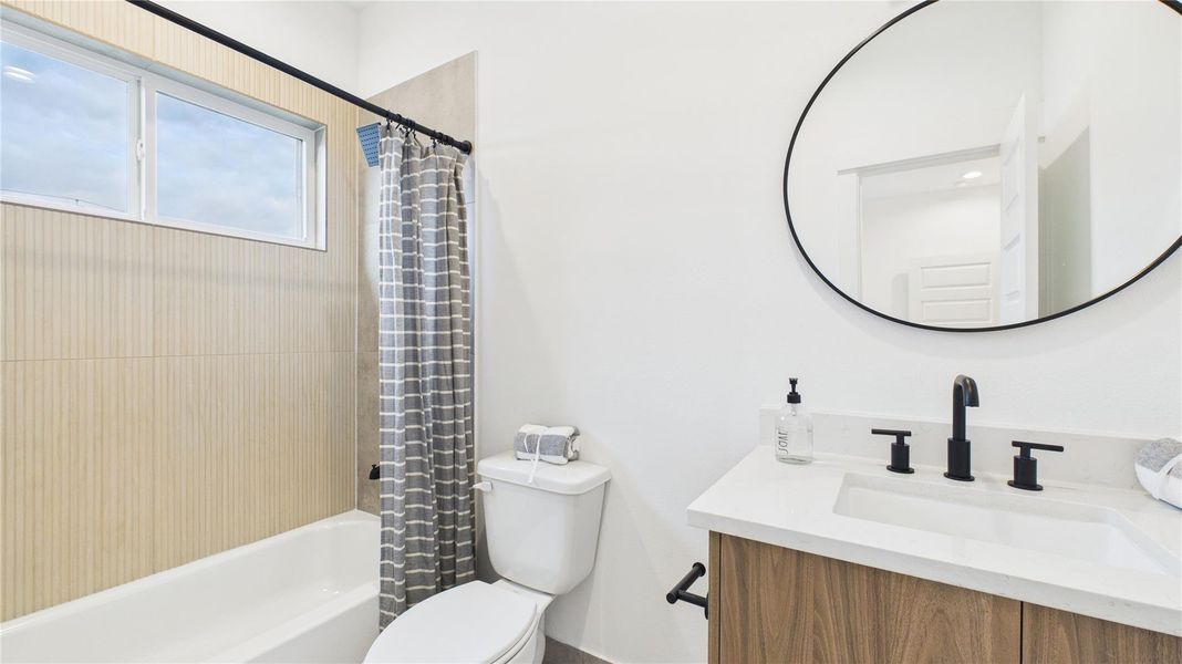 The ensuite bathroom of the second secondary bedroom features a tub/shower combo and a sleek quartz vanity, combining functionality with modern elegance for a comfortable and stylish space.