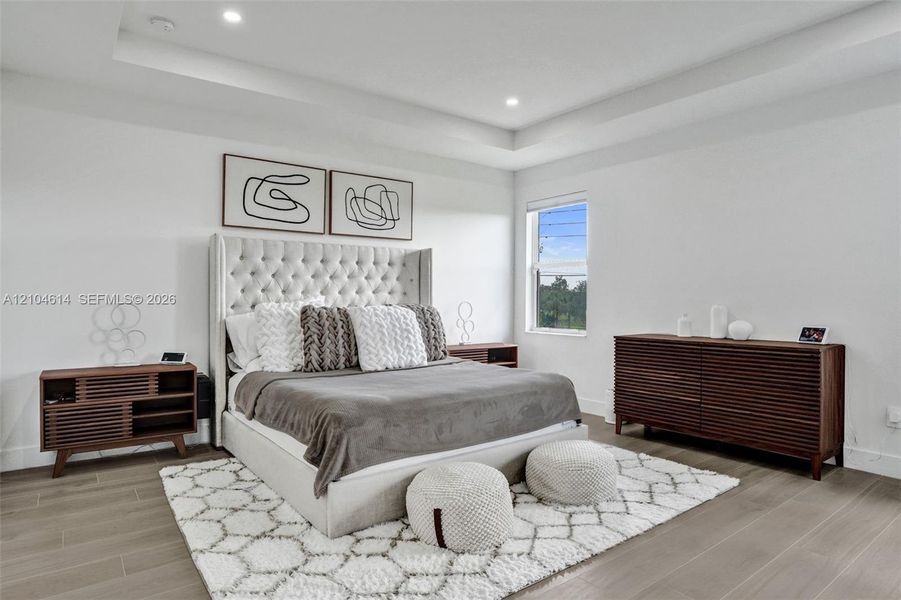 Recessed lighting, tray ceiling, and light wood look flooring