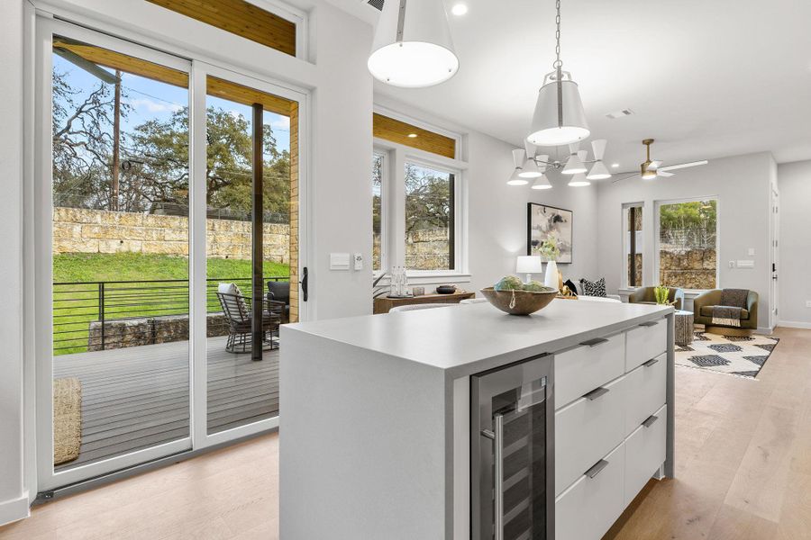 Kitchen with light wood-style flooring, beverage cooler, white cabinets, modern cabinets, and pendant lighting