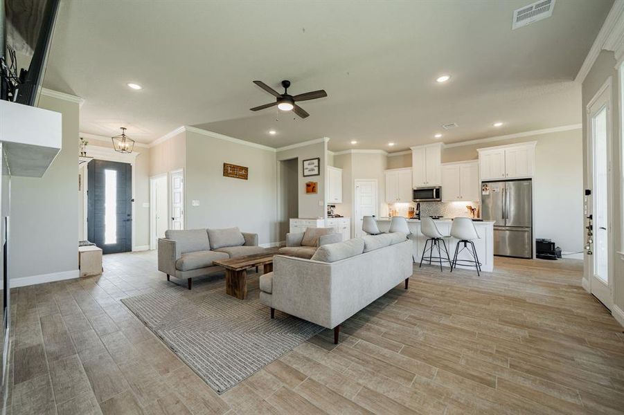 Living room featuring crown molding, recessed lighting, a ceiling fan, and light wood-type flooring Living room featuring crown molding, recessed lighting, a ceiling fan, and light wood-type flooring