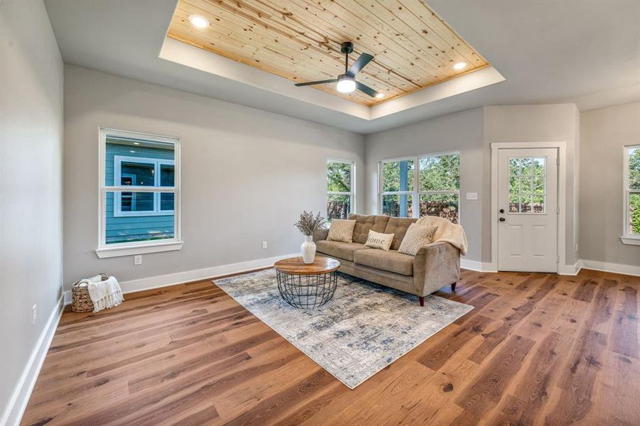Living area featuring a raised ceiling, wooden ceiling, wood finished floors, ceiling fan, and recessed lighting Living area featuring a raised ceiling, wooden ceiling, wood finished floors, ceiling fan, and recessed lighting