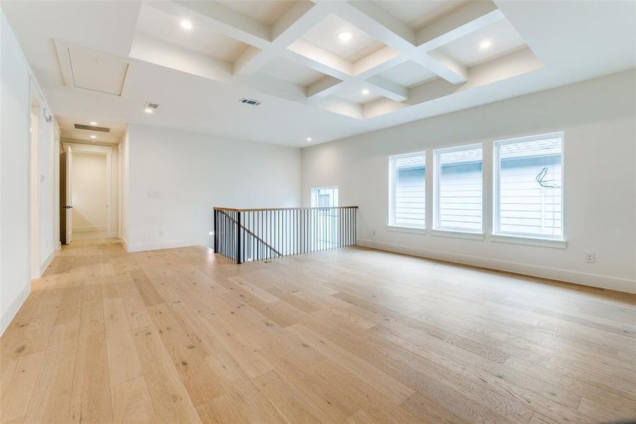 Spare room with coffered ceiling, beam ceiling, and light wood-type flooring