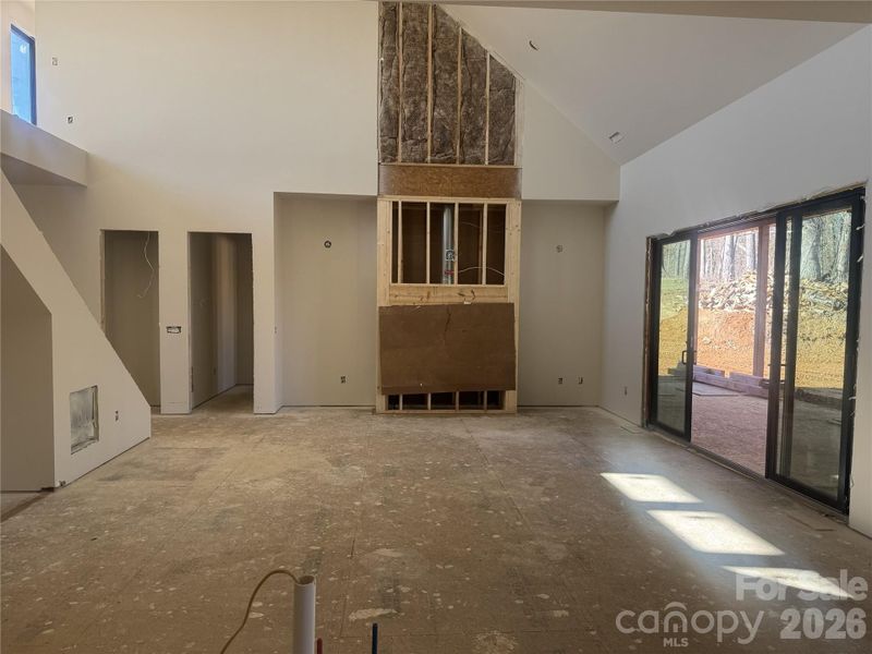 Great room showcasing a floor-to-ceiling stone fireplace and impressive 20-foot ceiling height, with sliding glass doors opening to the private outdoor deck. Great room showcasing a floor-to-ceiling stone fireplace and impressive 20-foot ceiling height, with sliding glass doors opening to the private outdoor deck.