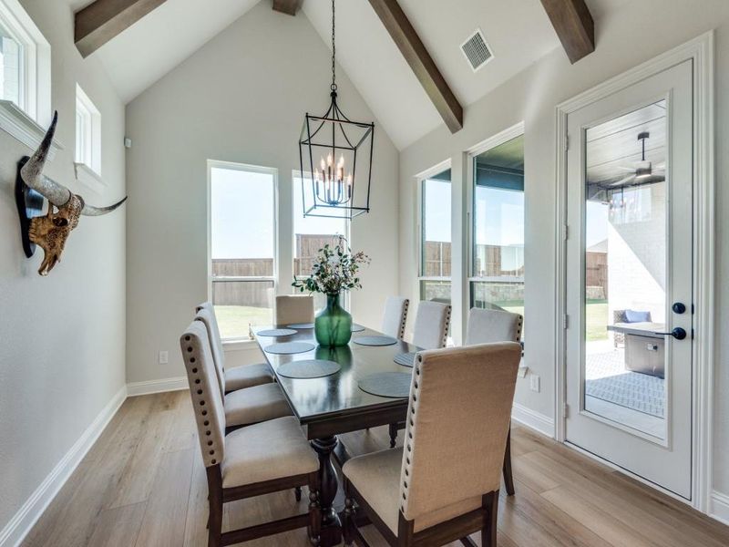 Dining area featuring light hardwood / wood-style floors, an inviting chandelier, beam ceiling, and high vaulted ceiling