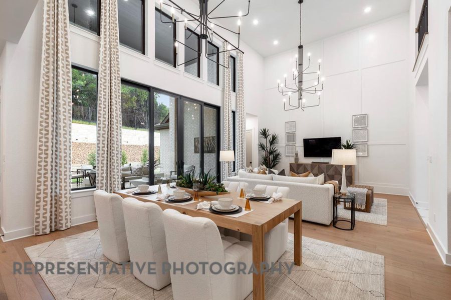 Dining room with a chandelier, light wood finished floors, baseboards, a towering ceiling, and recessed lighting Dining room with a chandelier, light wood finished floors, baseboards, a towering ceiling, and recessed lighting